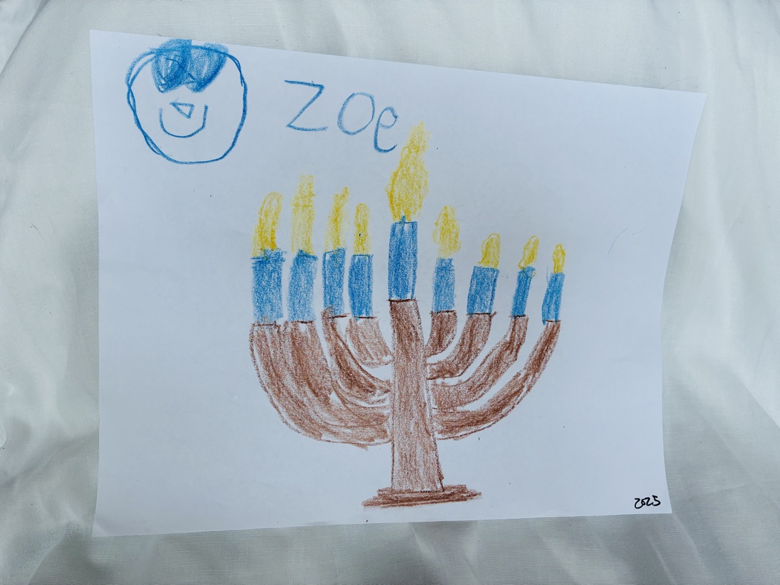 Crayon drawing of a lit hanukkiah with blue and brown candles, a small blue self-portrait in the corner
